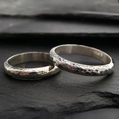 two silver rings sitting on top of a black surface