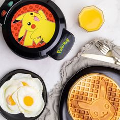 waffles, eggs and syrup are on the table with pokemon themed plates next to them