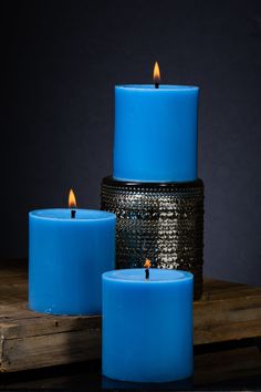 three blue candles sitting on top of a wooden table