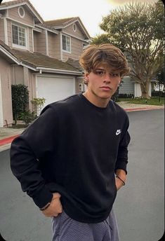 a young man standing in the middle of a street with his hands on his hips