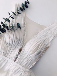 the back of a white dress with green leaves on it and lace trimmings