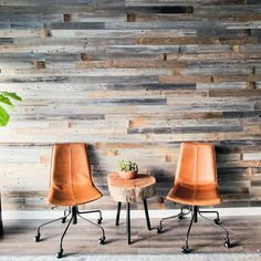 two chairs and a table in front of a wall with wood planks on it