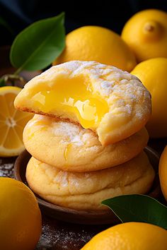 a stack of lemon cookies sitting on top of a wooden plate next to oranges