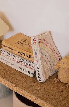 a stack of books sitting on top of a counter next to a small stuffed animal