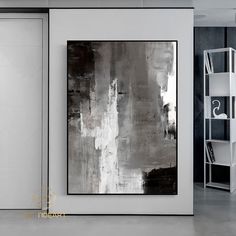 an abstract painting hangs on the wall next to a bookshelf and shelving unit