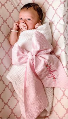 a baby wrapped in a pink blanket laying on top of a bed