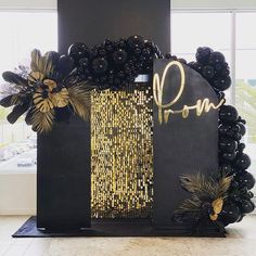 a black and gold party decoration with balloons in the shape of flowers, leaves and letters