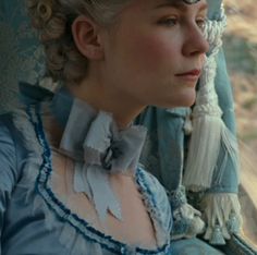 a woman wearing a blue dress sitting in a car looking out the window at something