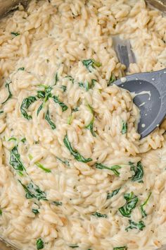 a pot filled with pasta and spinach on top of a stove