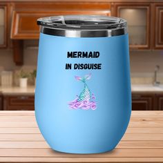 a blue wine tumbler with the words mermaid in disguise on it sitting on a wooden table