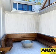 a wooden bench sitting under a skylight on top of a white tiled floor next to a window