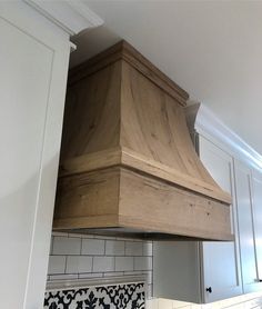 a wooden stove hood in a white kitchen