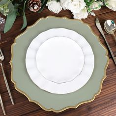 a table setting with white and green plates, silverware and flowers on the table