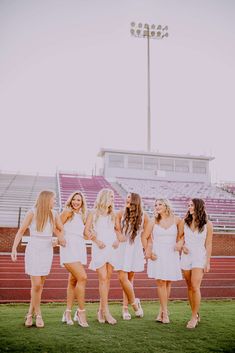 a group of women standing next to each other in front of a stadium bleachers