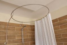 a shower with a white curtain next to a brown tiled wall