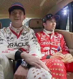 two men sitting in the back seat of a car wearing racing uniforms and hats with stars on them