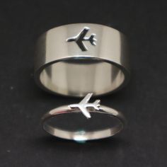 an airplane is engraved on the side of a silver ring that sits on a black surface