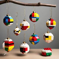 a group of lego ornaments hanging from a tree branch on top of a wooden table