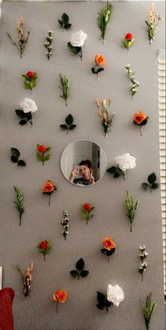 there are many flowers on the wall and one is taking a selfie in the mirror