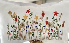 a white pillow with embroidered flowers on it