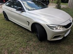 a white car parked on top of a grass covered field