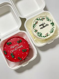 two plastic trays with christmas themed cakes in them, one is white and the other has red frosting