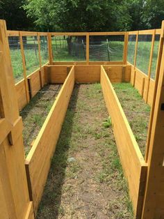 an outdoor area with several wooden raised planters and fencing around the perimeter, along with grass