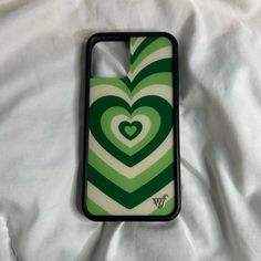 a green and white case with a heart design on it sitting on a bed sheet