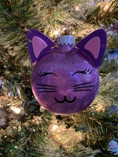 a purple cat ornament hanging from a christmas tree