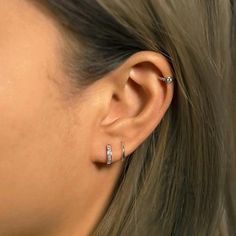 a close up of a person with ear piercings on their ears and behind them is a woman's head