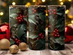 three glass vases decorated with holly and red berries on a wooden table next to christmas decorations