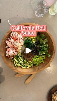 a wooden bowl filled with assorted veggies on top of a white counter