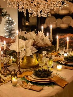 a dining room table is set with candles and flowers in vases, plates and napkins