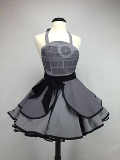 a dress on a mannequin with a black ribbon around the waist and an apron over it