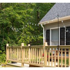 a porch with lights strung from it and trees in the backgrouds behind