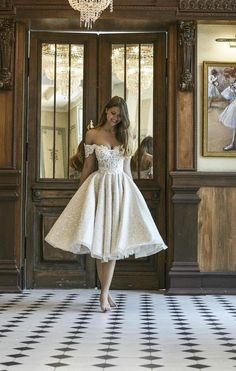 a woman standing in front of a doorway wearing a white dress