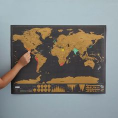 a person is pointing to a map on the wall with different colored pins and markers