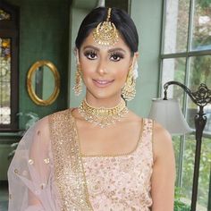 a woman in a pink outfit with gold jewelry on her neck and shoulders, posing for the camera