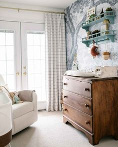 a baby's room with blue and white wallpaper on the walls, wooden furniture and shelves