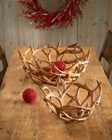 a wooden table topped with antlers and raspberries next to a red berry wreath