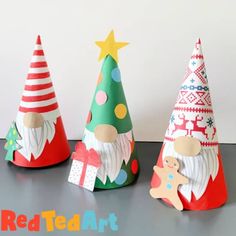 three paper christmas trees are sitting on the table, one has a santa clause hat