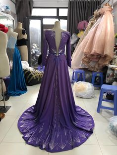 a purple dress is on display in a room full of mannequins and dresses