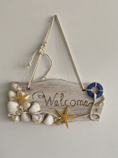 a welcome sign hanging from the side of a wall with seashells and starfish