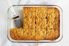 a glass baking dish filled with squares of food and a spatula on the side