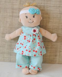 a small doll with a blue dress and flower on it's head is standing against a wall