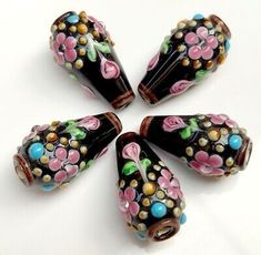 five black and pink glass beads with flowers on them