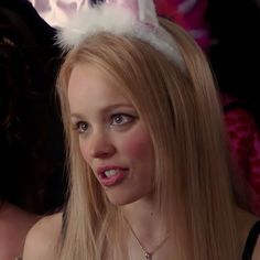 a woman with long blonde hair wearing a bunny ears headband and looking at the camera