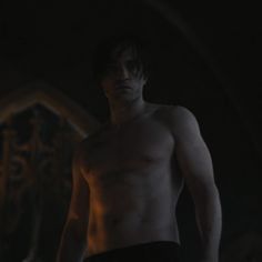 a shirtless man standing in the dark