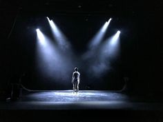 a person standing on a stage with three spotlights