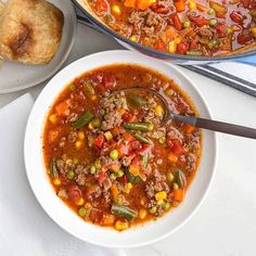 a white bowl filled with soup next to a muffin